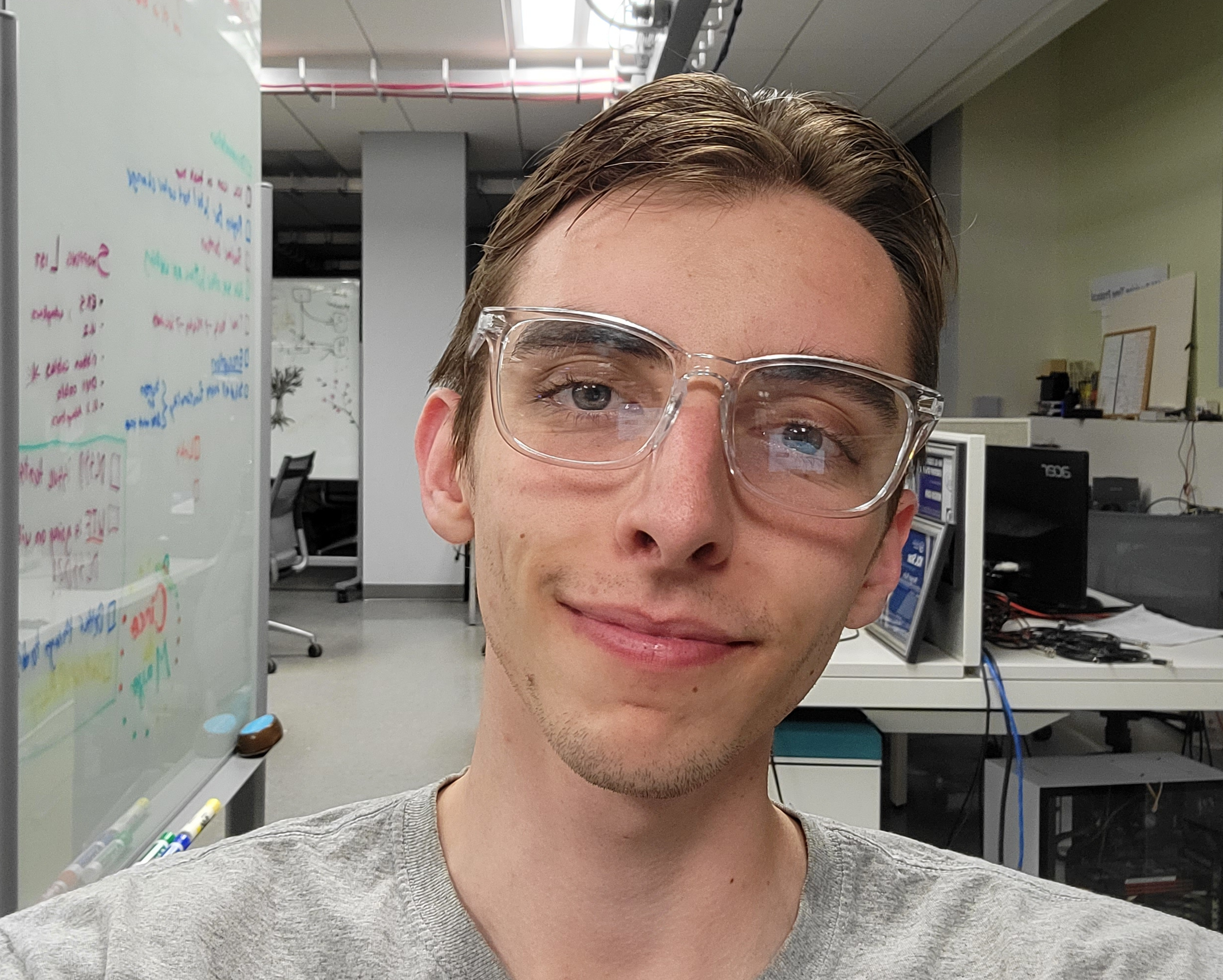 A headshot of Noah smiling with glasses on.